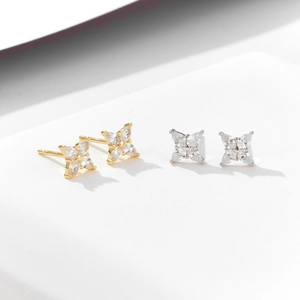 Minimalist silver four-leaf clover stud earrings with zircon crystals in gold and silver