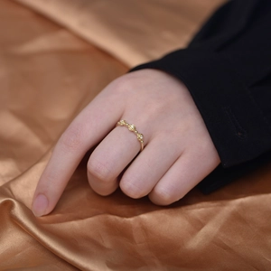 Macro shot of three golden rose rings with diamond accents on a satin fabric background
