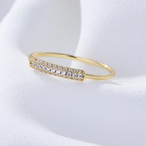 Detail shot of a gold pavé-set rectangular zircon ring on a white fabric background