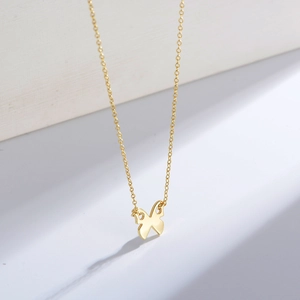 Detailansicht eines minimalistischen goldenen Schmetterlingsanhängers an einer Halskette