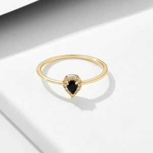 Gold ring featuring a black pear-cut gemstone surrounded by small white diamonds