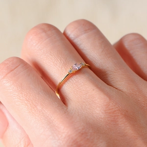 Close-up of elegant gold ring with oval pink zircon and small side stones on a finger