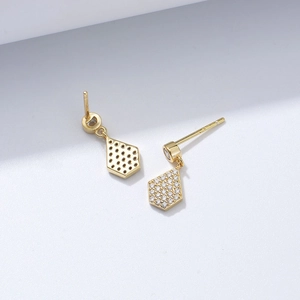 Macro detail of gold geometric kite earrings with pavé stones and honeycomb cutout back