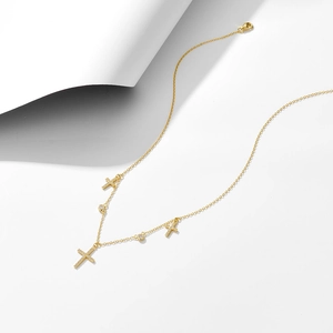 Macro shot of 925 silver cross necklace with pavé stones and gold plating details