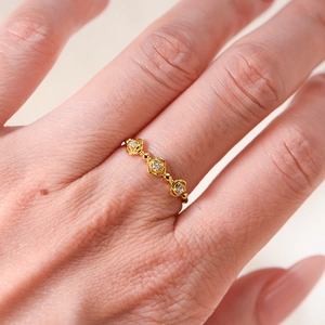 Golden sterling silver ring featuring three diamond-set roses worn on a model's finger