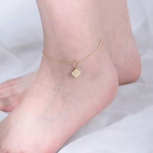 Detailed close-up of a gold shell pendant anklet with sparkling zircon on round bead chain