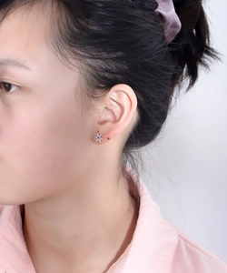 Close-up of star-shaped silver stud earring with blue gem and diamonds on ear