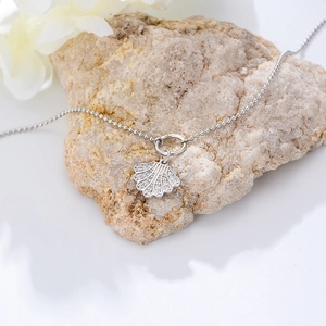 Close-up of sparkling rhinestone seashell pendant on a delicate silver bead chain