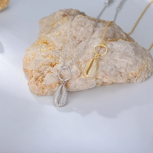 Close-up of gold and silver shell pendants with pavé zircons on natural stone display