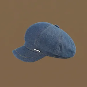 Detailed view of blue denim octagonal hat with metal logo tag and yellow topstitching