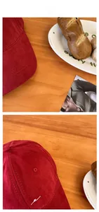 Detail of red corduroy baseball cap showing textured fabric and white cursive embroidery