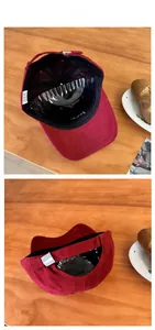 Detail view of burgundy baseball cap with adjustable metal buckle on a wooden desk