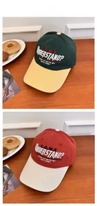 Detail of color-block baseball caps with C.O.M.E embroidery on a wooden surface
