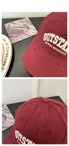 Macro shot of distressed burgundy cotton baseball cap with outstanding white embroidery