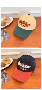 Detail view of two-tone cotton baseball caps with embroidered lettering on a wooden desk