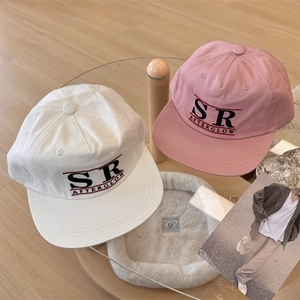 White and pink American retro baseball caps with SR AFTERGLOW embroidery on a glass table