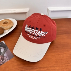 Vintage red and off-white baseball cap with embroidered text on a wooden table