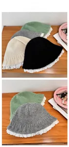 Detailed view of knitted bucket hats with white lace trim in green, grey, beige, and black
