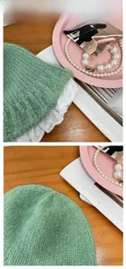 Detail of light green knitted bucket hat featuring intricate white lace trim and soft texture