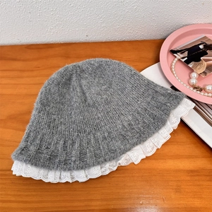Gray knitted bucket hat with white lace trim details on a rustic wooden table