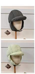 Detail view of winter earflap hats in olive and mint with windproof fabric and chin straps