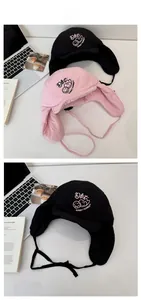 Detail of cute winter trapper hats in black and pink with embroidered flower design