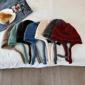Knitted earflap hats with long straps in various colors for winter outdoor warmth