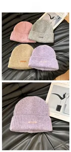 Detail of ribbed knit beanies with fluffy texture and stylish leather brand logo