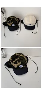 Detail view of camouflage and beige fleece trapper hats with earflaps and label