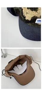 Detail of fleece camo trapper hat with denim brim showing inner lining and ear flaps