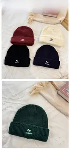 Detail of embroidered fox logo and distressed knit texture on various colored beanies