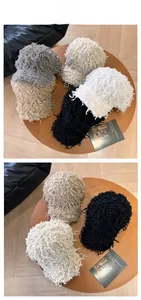 Detail shot of fringe knit baseball hats in grey and beige on a wooden tabletop