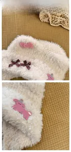 Close-up of fluffy cream plush hat with pink bows and cute puppy embroidery detail
