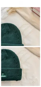 Detail of dark green ribbed knit beanie featuring vintage distressed holes and horse embroidery