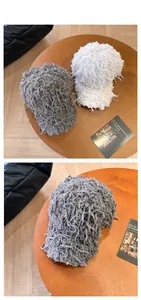 Close-up of grey and white long fringe plush baseball caps displayed on a wooden table