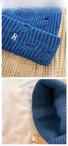 Detail of blue distressed knit beanie with white R letter embroidery and cable texture