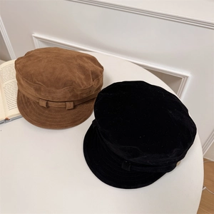 Casquettes gavroche vintage en daim marron et noir présentées sur une table blanche