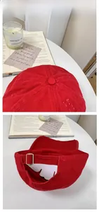 Detail view of red corduroy baseball cap with adjustable metal buckle on white background