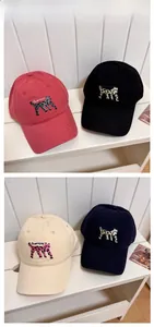 Detail of embroidered cat motifs on cotton baseball caps in four stylish colors