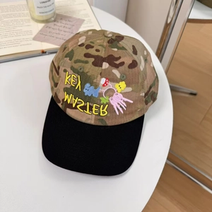 Camo baseball cap with colorful cartoon embroidery and wide black brim on white table