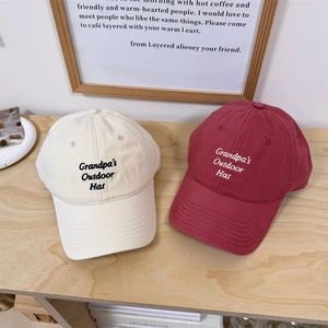 Classic embroidered baseball caps in cream and dark red on a rustic wooden table