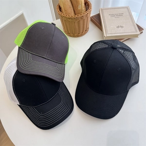 Three casual mesh trucker baseball caps in various colors on a white table for summer
