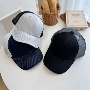 Three minimalist mesh baseball caps in black, navy and grey on a rustic white table