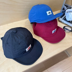 Outdoor quick-dry camping baseball caps in black, blue and wine red on a wooden desk