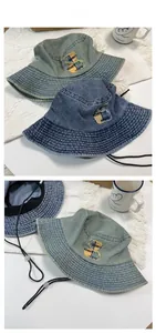 Detailed tile display of light and dark blue denim sun hats with HMMT embroidery