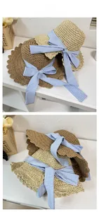 Detail of hand-woven straw hats in beige and brown with blue gingham bow ribbons