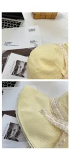 Detailed view of yellow plaid sun hat featuring delicate white lace trim and floral patterns