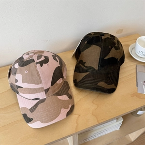 Outdoor camouflage baseball caps in pink and olive green shown on a wooden table