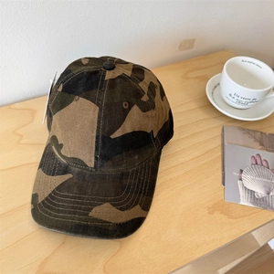 Classic jungle camouflage cotton baseball cap on a rustic wooden desk with accessories