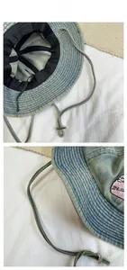 Detailed view of denim bucket hat showing pink embroidery and adjustable windproof strap